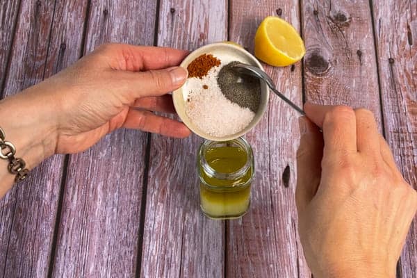 Für das Brotsalat Dressing werden Olivenöl, Zitronensaft, Salz, Pfeffer und Chili in ein Schraubglas gefüllt