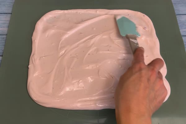Gesüßter Joghurt wird auf einem mit einem Backpapier ausgelegten Brett verteilt.