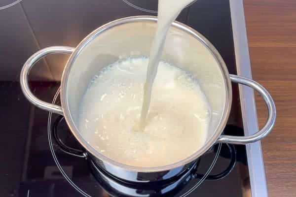 Milch wird in einen Kochtopf gegossen, um High Protein Pudding selber zu machen