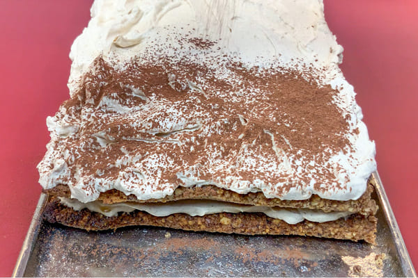 Low carb Lebkuchen Tiramisu auf einer Platte, das mit Kakao bestäubt wird
