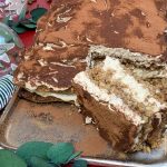 Angeschnittenes low carb Lebkuchen Tiramisu auf einem Tablett mit Kaffeebohnen, Haselnüssen und Weihnachtskugeln