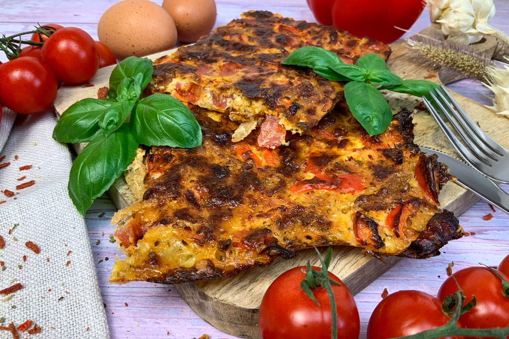 Vegetarische low carb Schüttelpizza mit Tomaten, Basilikum, Paprika und Eiern auf einem Holzbrett