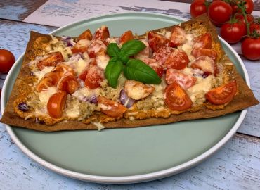 Low carb Pizza mit Thunfisch, Tomaten und Käse auf einem Teller angerichtet