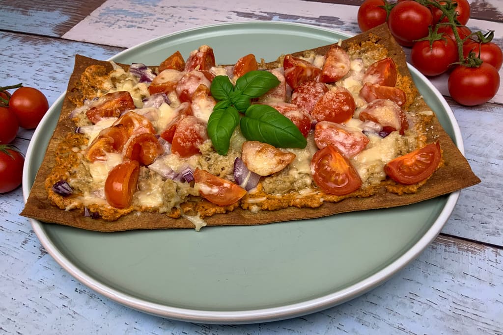 Low carb Pizza mit Thunfisch, Tomaten und Käse auf einem Teller angerichtet