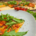 Fertig gebackener High Protein Pizzateig belegt mit Salami, Tomaten, Käse und Rucola