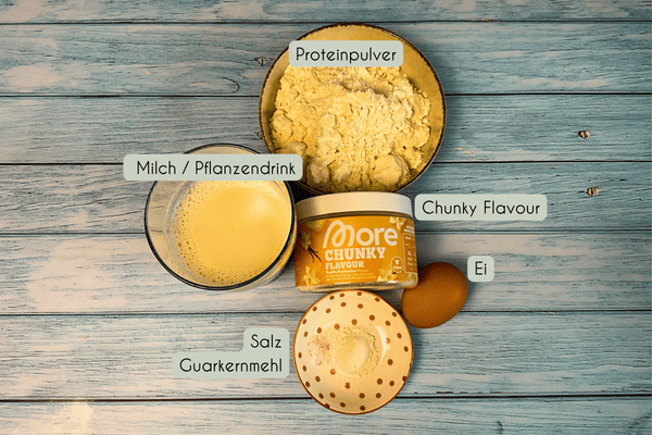 Zutaten für das Proteinpudding Rezept in Schälchen: Proteinpulver, Milch oder Pflanzendrink, Chunky Flavour von More Nutrition, Salz, Guarkernmehl und ein Ei