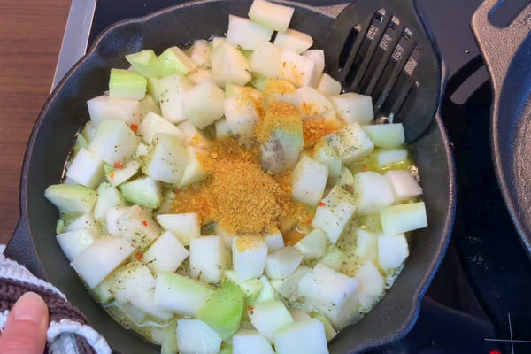 Kohlrabiwürfel in einer Pfanne mit Butter, Gemüsebrühe, Salz, Pfeffer und gemahlener Zitronenschale