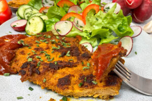 Veganes Steak Rezept mit leckerer Marinade: Angeschnittenes veganes Steak mit Barbecue Sauce und Salat auf einem Teller