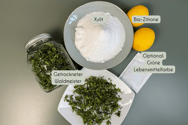 Zutaten für Waldmeister Sirup ohne Zucker: Getrockneter Waldmeister, Xylit, Zitrone und optional grüne Lebensmittelfarbe